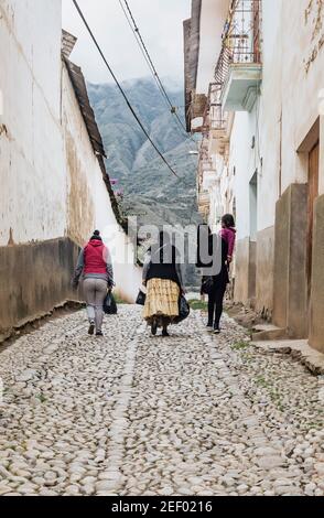 SORATA, BOLIVIEN - 29. JANUAR 2018: Eine Gruppe von Frauen mit einem Mädchen geht durch eine gepflasterte Straße mit Bergen im Hintergrund im kolonialen t Stockfoto