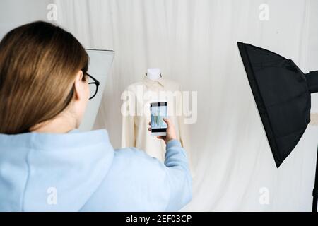AR VR-Technologie in der Modeindustrie. Weibliche Designer Schrottung Kleidung auf Schaufensterpuppe per Handy für Augmented Reality Anwendung. AR VR-Lösungen Stockfoto