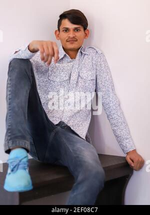 Vertikale Aufnahme eines jungen lächelnden Indianers, auf dem er sitzt Ein Stuhl Stockfoto