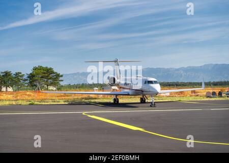 Kleines Flugzeug, das am Flughafen geparkt wurde. Verwendung von Privatjets zur Vermeidung von Coronavirus-Risiken und -Einschränkungen. Dinaric Alpen Berge im Hintergrund, Zadar, Kroatien Stockfoto