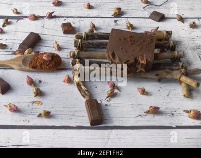 Schokoladenseife und Rosen in einer Seifenschale, auf weißem Holzhintergrund Stockfoto