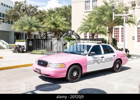 Ein stillgelegter Polizeiwagen von Miami Beach, der vor dem alten Rathaus pink gestrichen wurde, mit dem Miami Beach Police Officers' Memorial im Hintergrund, in Miami Beach. Stockfoto