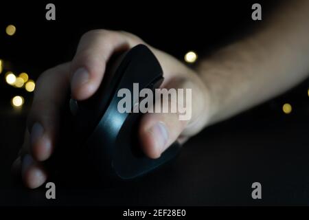 Moderne vertikale drahtlose Maus mit einer Hand Designer, Gamer bedient. Schwarzer Hintergrund mit Lichtern. Ergonomische Maus. Karpaltunnelsyndrom rot Stockfoto