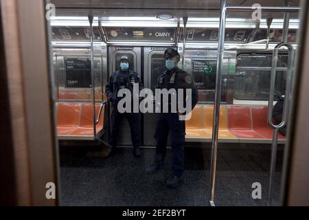 New York, USA. Februar 2021, 16th. Zwei NYPD-Offiziere fahren mit einem lokalen Zug 6 in der Innenstadt, der die U-Bahn-Station Union Square in Manhattan verlässt, während die NYPD 644 Polizeibeamte hinzufügt, um die U-Bahnen zu patrouillieren, nachdem ein obdachloser Mann am Wochenende zwei Personen im ZUG A erstochen und getötet hatte, New York, NY, 16. Februar 2021. (Foto von Anthony Behar/Sipa USA) Quelle: SIPA USA/Alamy Live News Stockfoto