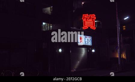 Das rote Neonschild eines Tokioter Pfandladens bei Nacht. Stockfoto