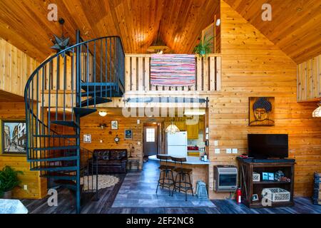 Innenansicht eines gehobenen rustikalen Blockhauses mit hölzernen Zedernholzplanken, Dachboden und Wendeltreppe. Stockfoto