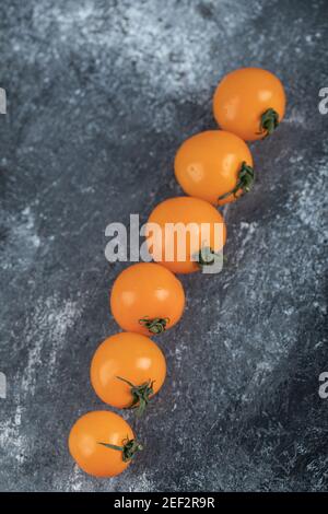 Gelbe Kirschtomaten in einer Reihe auf grauem Hintergrund Stockfoto