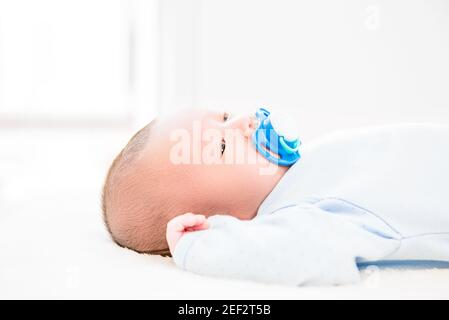 Liebenswert kleines neugeborenes Baby mit Dummy auf dem Bett liegen Stockfoto