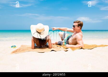 Pärchen liegen am weißen Sandstrand und entspannen sich und nehmen ein Sonnenbaden im Sommer Stockfoto