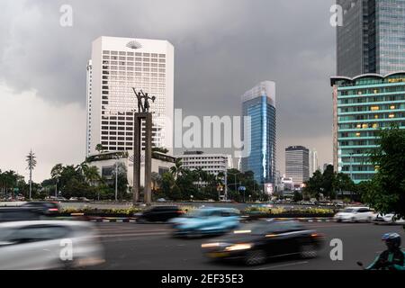 Jakarta, Indonesien - November 23 2019: Der Verkehr fährt entlang der Thamrin Avenue im Jakarta Geschäfts- und Finanzviertel vor einem schweren tropischen Stor Stockfoto