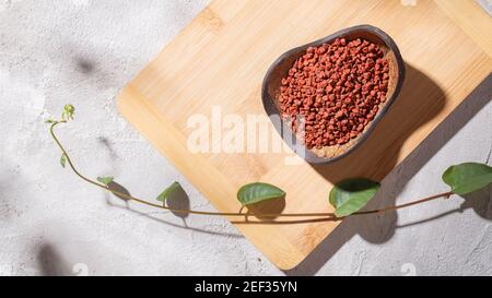 Achiote Körner in Holzschale auf weißem Hintergrund (Bixa orellana) Stockfoto