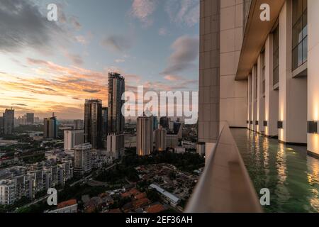 Jakarta, Indonesien - November 4 2019: Die Sonne untergeht über der Skyline von Jakarta vom Swimmingpool eines hohen Wohnturms in der indonesischen Hauptstadt. Stockfoto