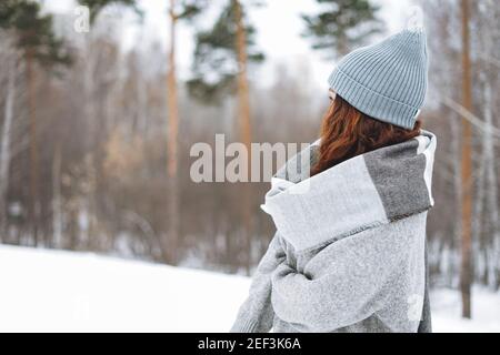 Attraktive junge Frau in Strickmütze und kuschelig grauem Pullover Im Winterpark Stockfoto