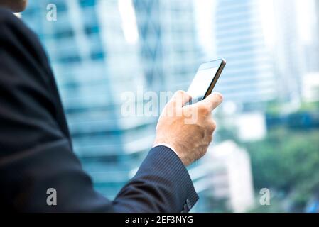 Geschäftsmann mit Smartphone neben Bürogebäude Fenster in der Stadt Stockfoto