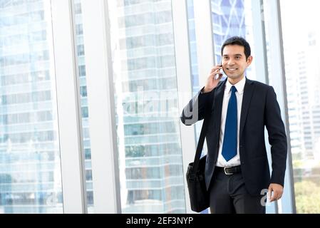 Hübscher asiatischer Geschäftsmann, der beim Einlaufen auf dem Handy anruft Flur im Gebäude Stockfoto