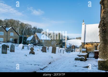 St. Barnabas Kirchhof im Januar Schnee. Snowshill, Cotswolds, Gloucestershire, England Stockfoto