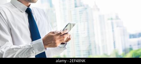 Geschäftsmann mit Smartphone neben Bürogebäude Fenster in der Stadt - Panorama-Banner Stockfoto