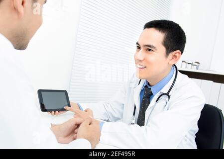 Arzt spricht und erklärt dem Patienten die Behandlung mit einer Tablette Computer Stockfoto