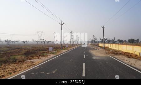 10. Februar 2021- Sikar, Jaipur, Indien. National Highway Road für den Transport. Schwarze Asphaltstraße mit weißer Linie und parallelen Strommasten. Stockfoto