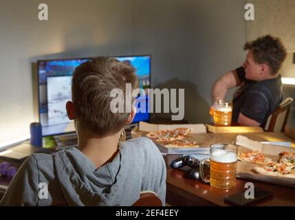 Jungs Nacht. Zwei Männer schauen fern, trinken Bier und essen Pizza Stockfoto