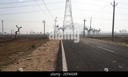 10. Februar 2021- Sikar, Jaipur, Indien. Morgendliche Aufnahme einer leeren Industriestraße vor Hochspannungsmasten. Straße ohne Verkehr von Indu Stockfoto