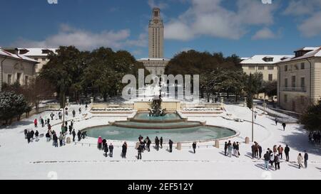 Austin, Texas - 15. Februar 2021: Studenten spielen im Schnee in der Nähe der University of Texas Brunnen und Turm nach einem Schneesturm Stockfoto