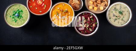 Vegane Suppe panoramischer Banner mit Kopierraum. Gemüsecremesuppen, von oben auf schwarzem Hintergrund geschossen Stockfoto