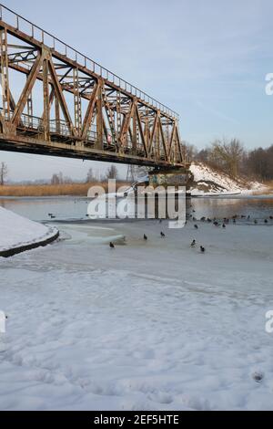 Stadt Riga, Lettland. Alte Eisenbahnbrücke und Fluss im Winter.Reisefoto 23.01.2021 Stockfoto