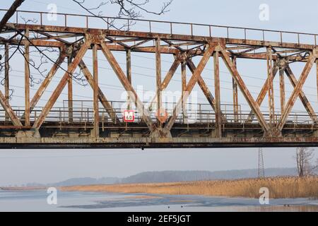 Stadt Riga, Lettland. Alte Eisenbahnbrücke und Fluss im Winter.Reisefoto 23.01.2021 Stockfoto