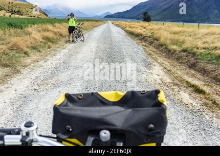 Queenstown Neuseeland - März 2 2015; Radler mit einem Off-Bike fotografieren entlang der langen staubigen Landstraße durch Berge und Felder am Lake W Stockfoto