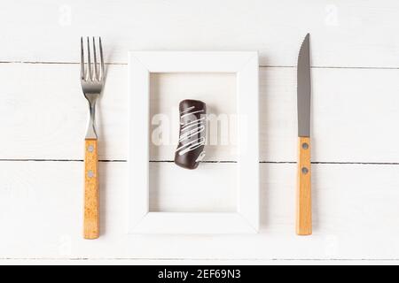 Gesunde Ernährung und Diät-Konzept. Kleines Dessert in einem Fotorahmen serviert mit Gabel und Messer auf weißem Tisch. Stockfoto