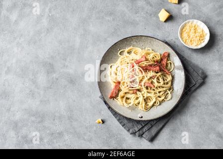 Spaghetti Carbonara auf grauem Tisch. Hausgemachte Pasta mit Speck, Ei, hartem Parmesan und Sahnesauce. Traditionelle italienische Küche. Pasta alla Carb Stockfoto