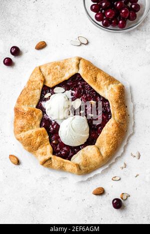 Kirschgalette mit Mandeln und Vanilleeis auf weiß, Draufsicht, Kopierraum. Hausgemachte gesunde Dessert - Kirschkuchen oder französisch Galette. Stockfoto