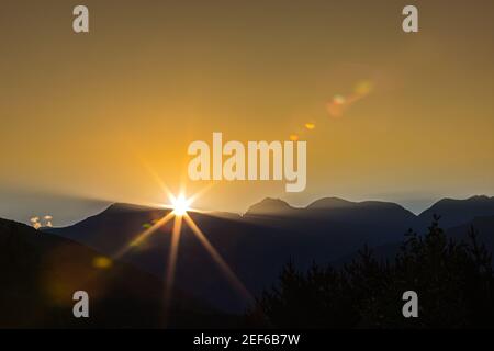 Am frühen Morgen in den Bergen, die ersten Strahlen der Sonne kommen über den Gipfeln des Grats. Herrliche faszinierende Landschaft. Stockfoto