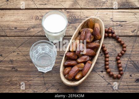 Die getrockneten Datteln die Früchte auf dem Zweig, die Gläser des Wassers und der Milch auf dem hölzernen Tisch. Traditionelle Fast Breaking, Muslime Abendessen während des heiligen Ramadan Stockfoto