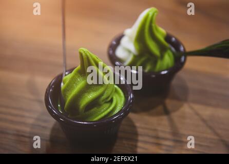 Matcha-Grüntee-Eis in einer Tasse auf einem Holztisch mit geringer Beleuchtung. Stockfoto