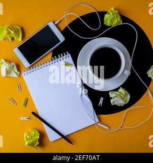 Tasse schwarzen Kaffee auf vynil Rekord. Speicherplatz für Notizbuch-Kopien. Musik hören. Retro-Style. Podcast. Mobiltelefon mit Kopfhörern. Stockfoto