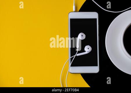 Tasse schwarzen Kaffee auf vynil Rekord. Speicherplatz kopieren. Musik hören. Retro-Style. Podcast. Mobiltelefon mit Kopfhörern. Stockfoto