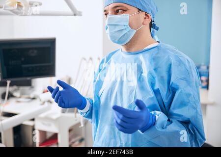 Kompetenter Stomatologe trägt sterile Uniform für die Arbeit Stockfoto