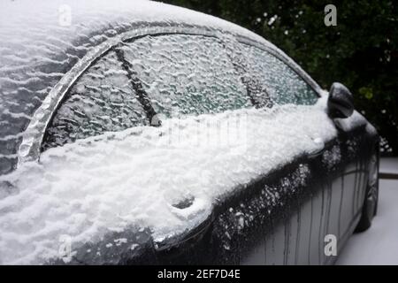 Nahaufnahme des gefrorenen Türgriffs und der Fenster eines Autos auf den Straßen nach einem Wintersturm von Schnee und eiskalten Regen. Stockfoto