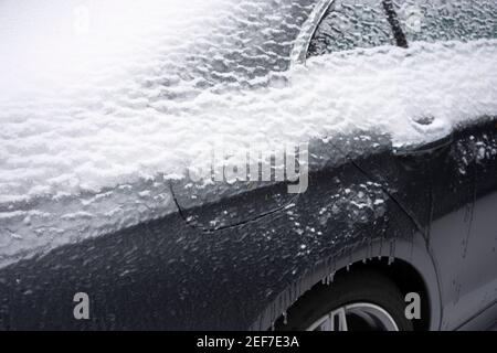 Nahaufnahme der gefrorenen Gasabdeckung und des Türgriffs eines Autos auf der Straße nach einem Wintersturm von Schnee und eiskalten Regen. Stockfoto