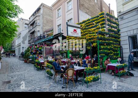 Blumen in Töpfen auf dem historischen Platz Skadarlija mit Bäumen, Cafés, gepflasterten Gassen und Gassen in der Innenstadt. Belgrader Straße mit Bars und Restaurants. Stockfoto