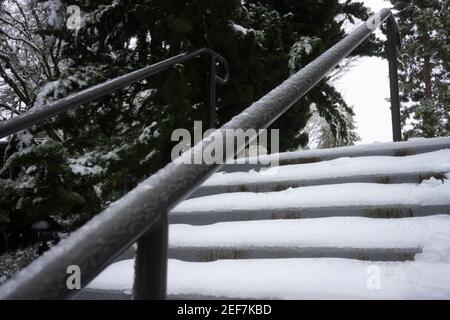 Verschneite Außentreppen und gefrorenes Geländer nach Schnee und eiskalten Regen im Winter. Stockfoto
