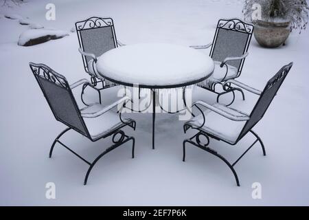 Gefrorener und schneebedeckter Tisch und Stühle im Freien nach Schnee und eiskalten Regen im Winter. Stockfoto