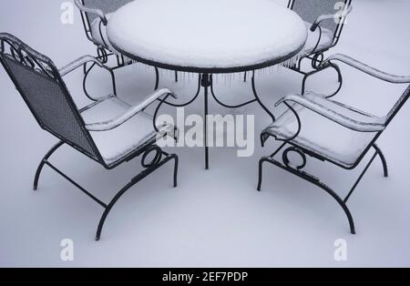 Gefrorener und schneebedeckter Tisch und Stühle im Freien nach Schnee und eiskalten Regen im Winter. Stockfoto