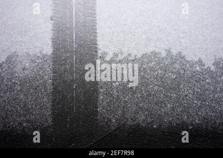 Autoreifen Spuren auf einer dünnen Schicht Schnee außerhalb der Garage. Stockfoto