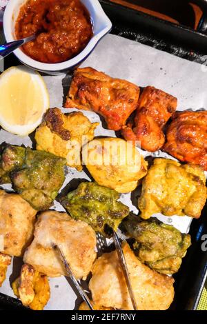 Vertikale Aufnahme von indischen gebratenen Huhn und Fisch mit in Scheiben geschnitten Zitrone auf weißem Papier Hintergrund Stockfoto