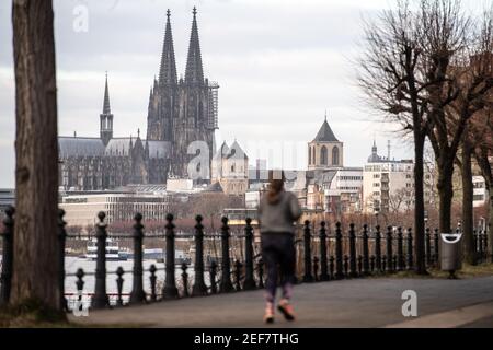 Landesweit, Deutschland. Februar 2021, 17th. Eine Frau joggt am Rheinufer entlang. Im Hintergrund ist der Kölner Dom zu sehen. Nordrhein-westfälischer Ministerpräsident Laschet (CDU) hat seinen Aufruf zu einem berechenbaren Kurs für die Bürger im Umgang mit der Corona-Krise wiederholt. (To dpa 'Laschet bekräftigt Forderung nach vorhersehbarem Lockdown Course') Quelle: Marius Becker/dpa/Alamy Live News Stockfoto