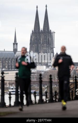 Landesweit, Deutschland. Februar 2021, 17th. Zwei Männer joggen am Rheinufer entlang. Im Hintergrund ist der Kölner Dom zu sehen. Nordrhein-westfälischer Ministerpräsident Laschet (CDU) hat seinen Aufruf zu einem berechenbaren Kurs für die Bürger im Umgang mit der Corona-Krise wiederholt. (To dpa 'Laschet bekräftigt Forderung nach vorhersehbarem Lockdown Course') Quelle: Marius Becker/dpa/Alamy Live News Stockfoto