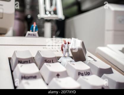 Computer IT Tastatur Reparatur wird von kleinen Technikern Menschen getan Schlüssel vom PC entfernt, um durch Waage gehalten zu reinigen Model Person in Arbeitskleidung Reparatur Stockfoto